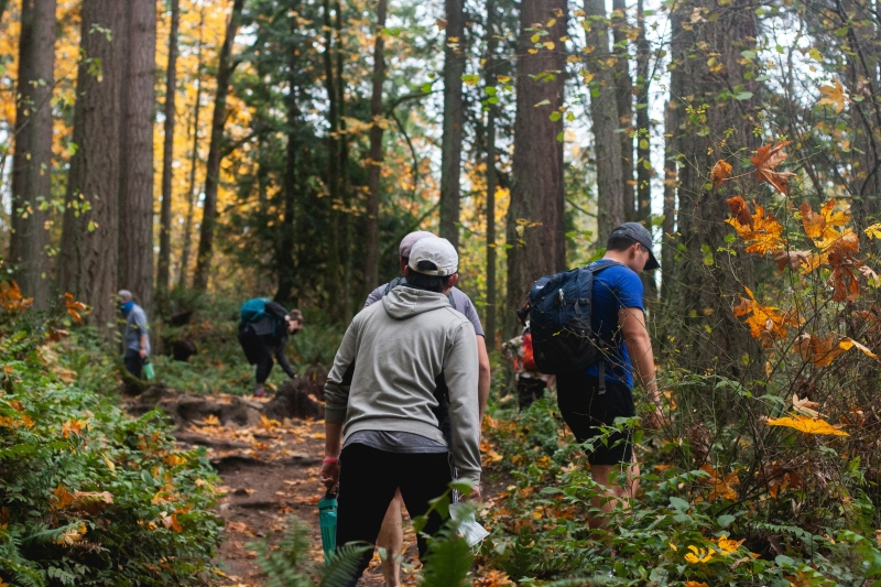 Una vista detrás de personas caminando y explorando un sendero boscoso.
