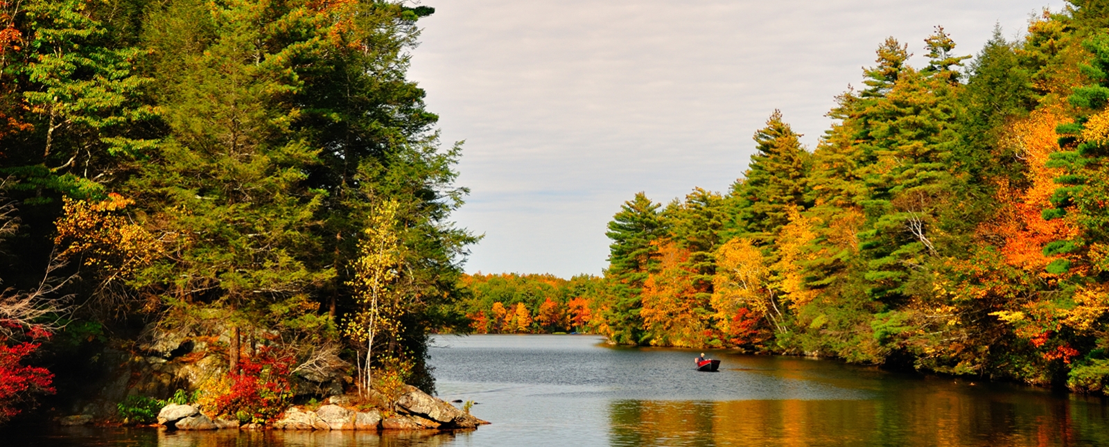 Man in motor boat on serene water at Bigelow Hollow State Park