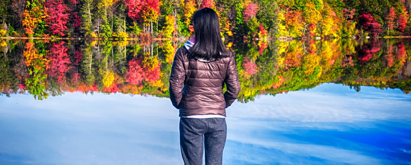 Mujer joven con vistas a Burr Pond durante el follaje de otoño