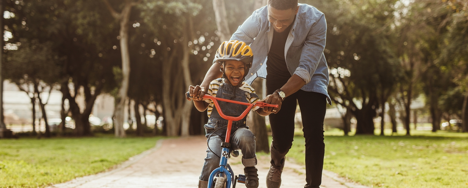 Father teaching son to ride his bike in state park