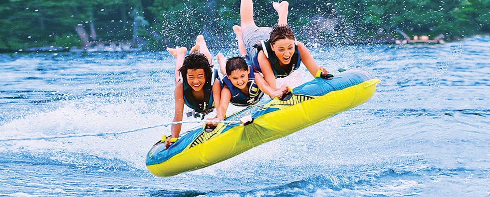 Three boys tubing behind boat on a lake