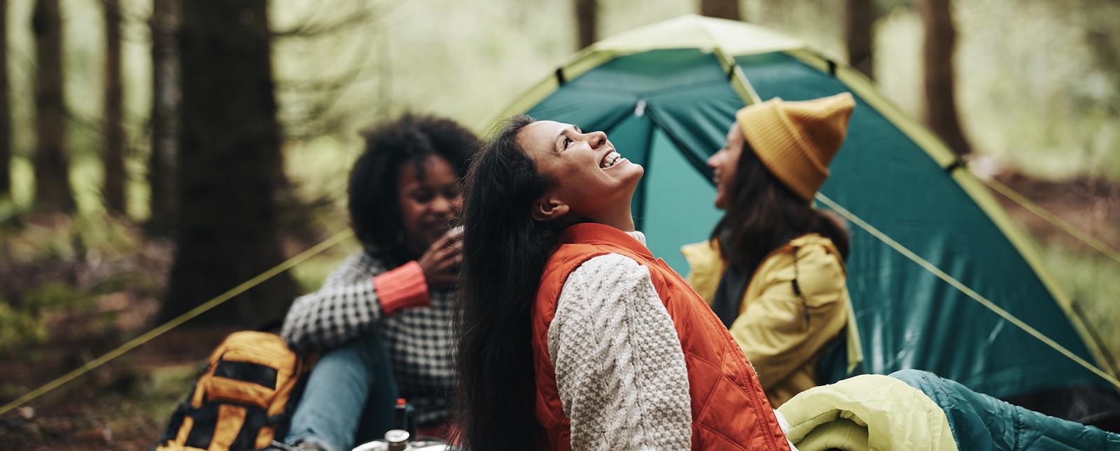 Tres mujeres disfrutando de la naturaleza mientras acampan