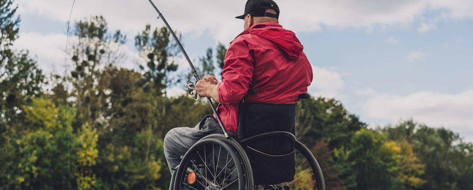 Anciano pescando en el muelle en silla de ruedas 