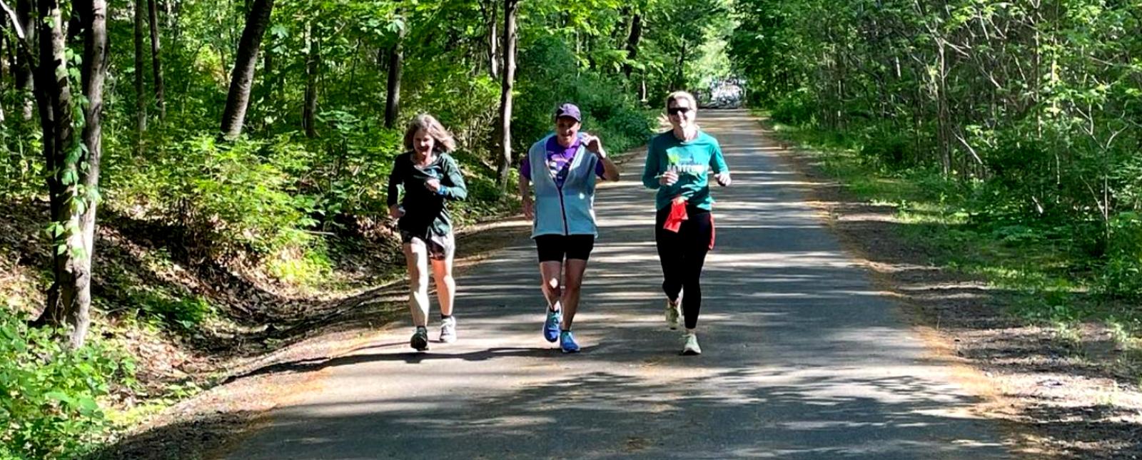 Tres mujeres corriendo por un camino en el bosque