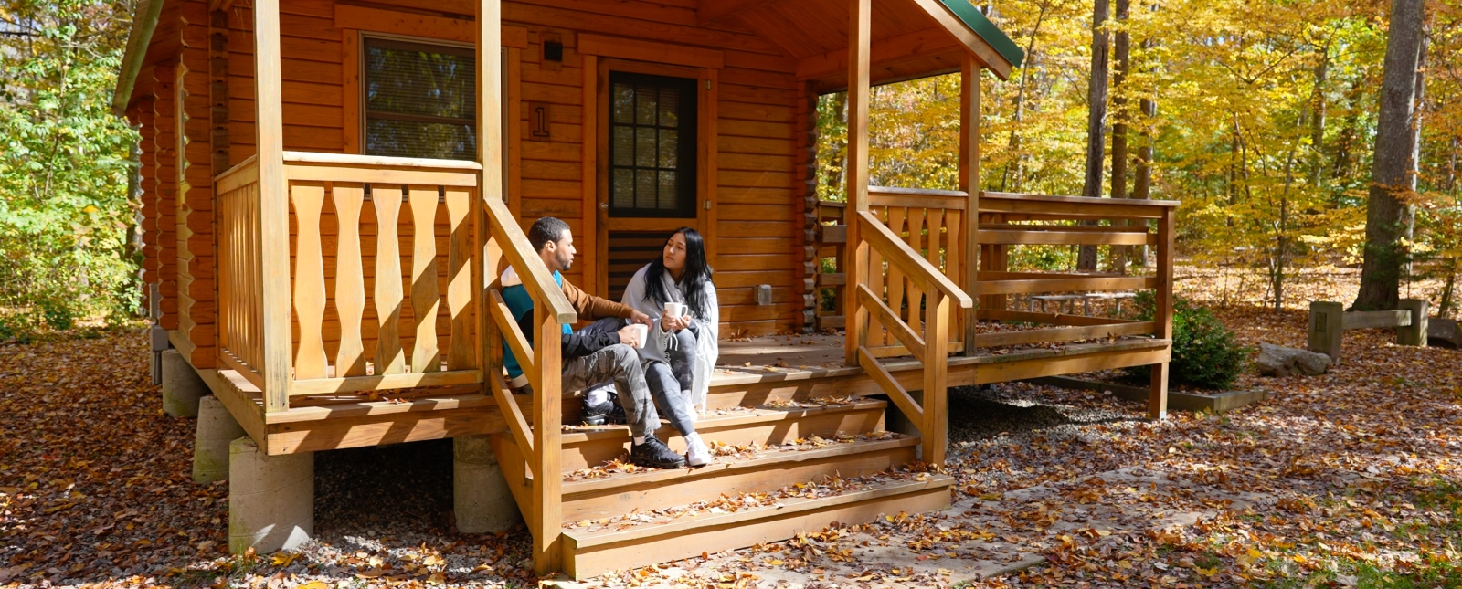 Pareja disfrutando de una taza de café en el porche del camping/cabaña Hopeville Pond