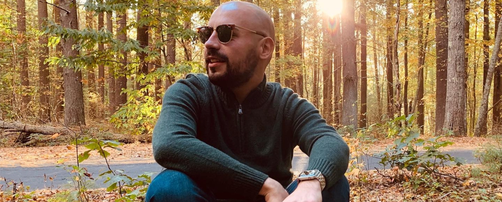 A man poses on a log holding leaves in the woods (Instagram@jonathan_antonio16)