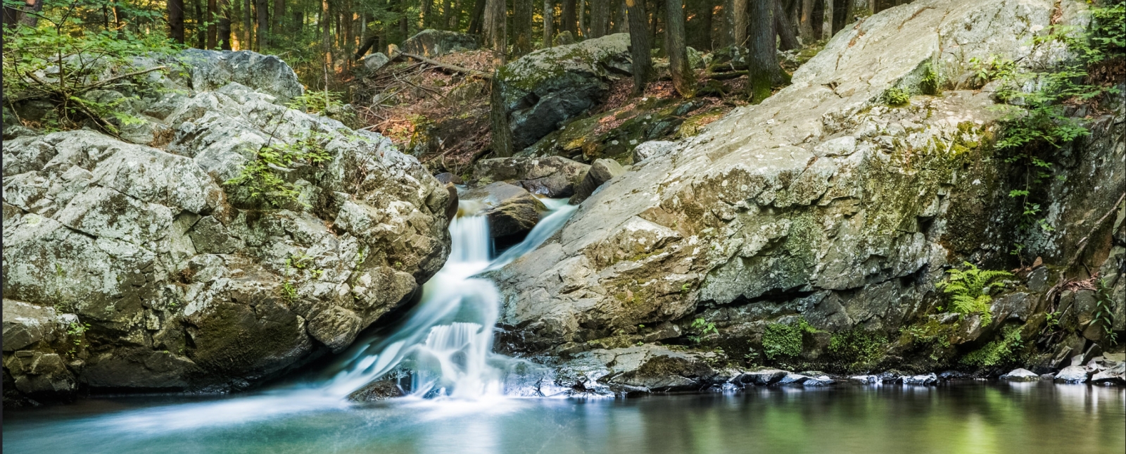 A waterfall flows from the woods (Flickr@Gerrett-Uhde)