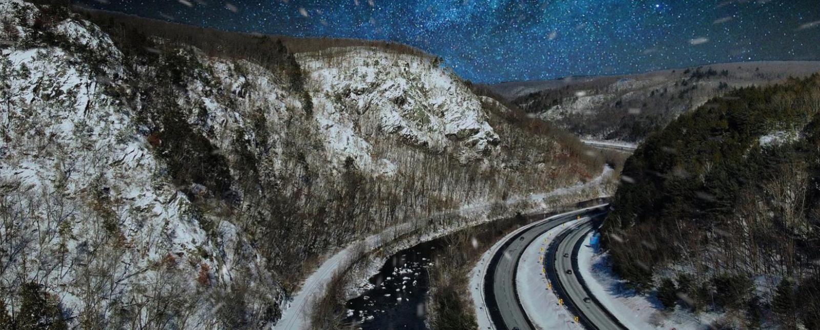 Highway going through snowy mountains at night (Instagram@dronesoverthevalley)