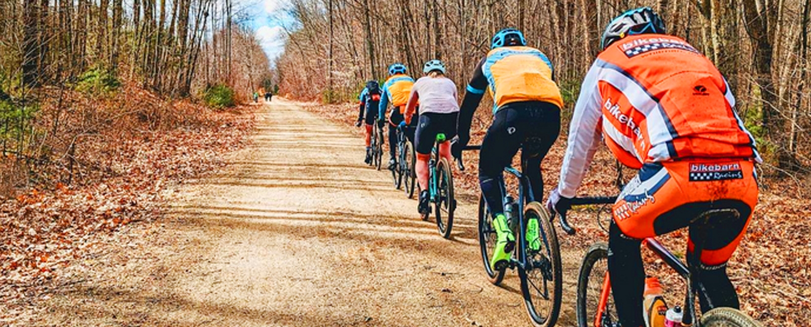 Un grupo de personas en bicicleta por un camino de tierra en el bosque.