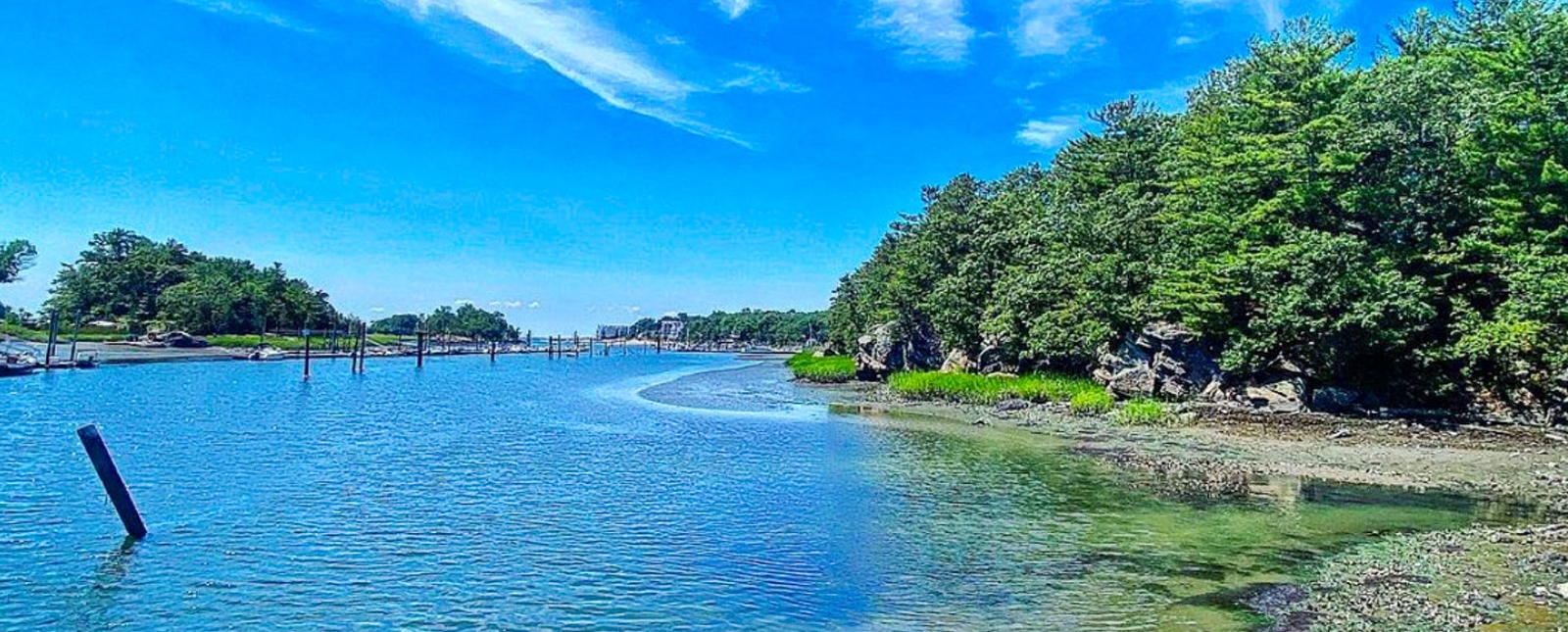 Vista panorámica de aguas tranquilas bajo un cielo azul con nubes esponjosas.