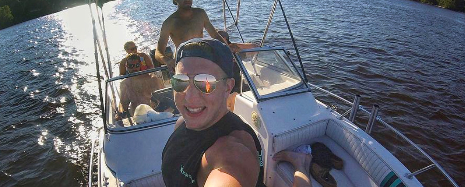 Un hombre sonriendo mientras se toma una selfie en un barco, capturando un momento de alegría en el agua.