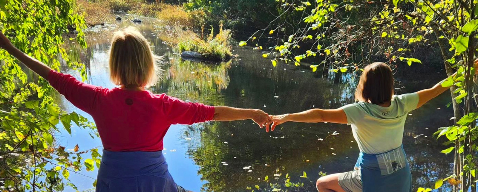 Dos mujeres posaron con gracia sobre una roca con vistas al agua.
