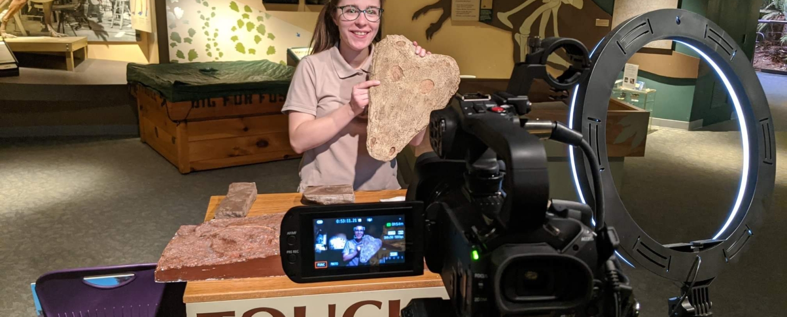Female educator showing fossils in front of a camera