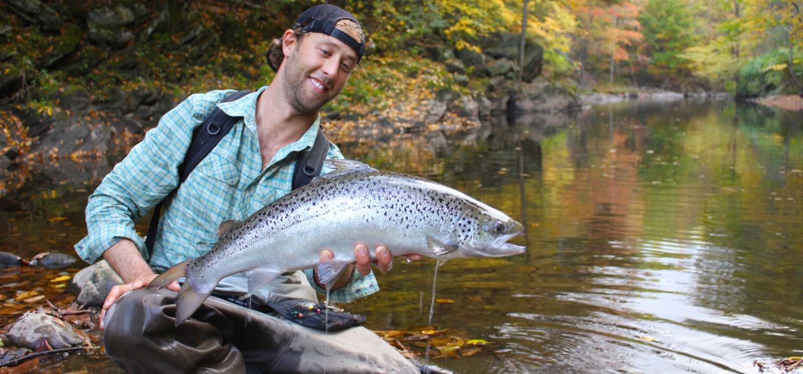 Man holding large fish along Farmington River