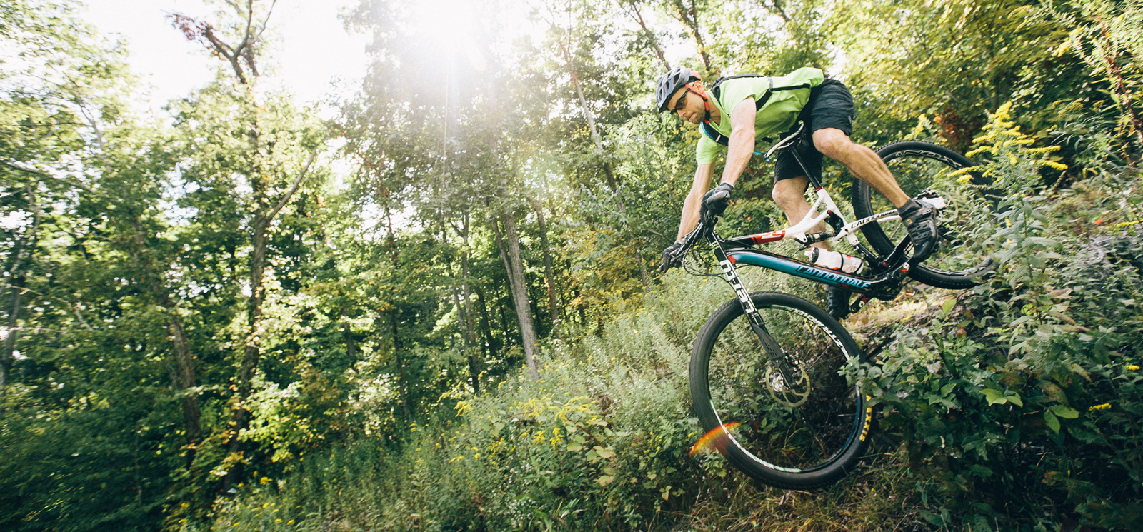 Hombre ciclismo de montaña a través de bosques