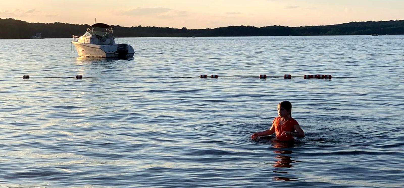 niña nadando en el lago con un barco al fondo (Instagram@sarateidee)