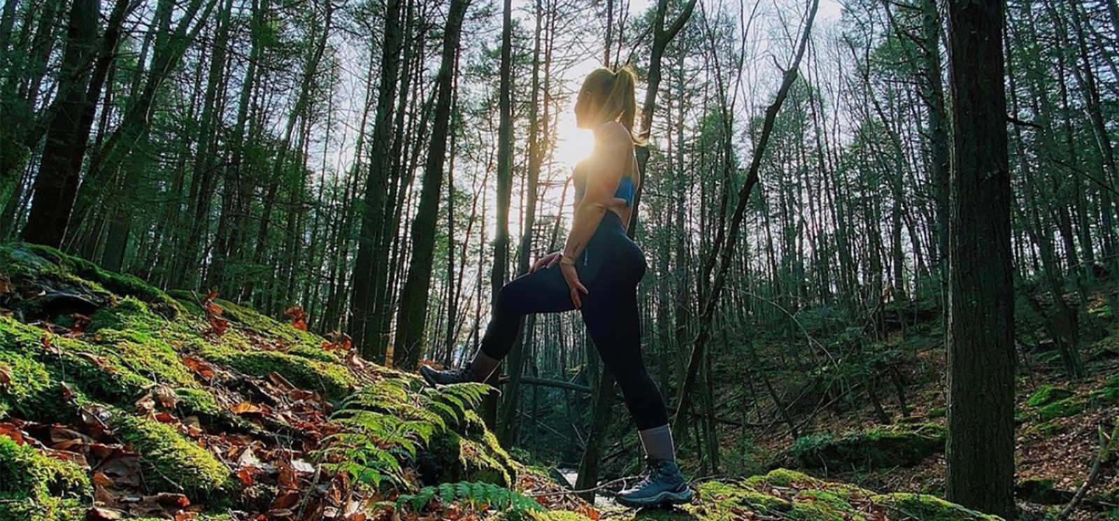 A woman hiking up hill through the woods in the fall