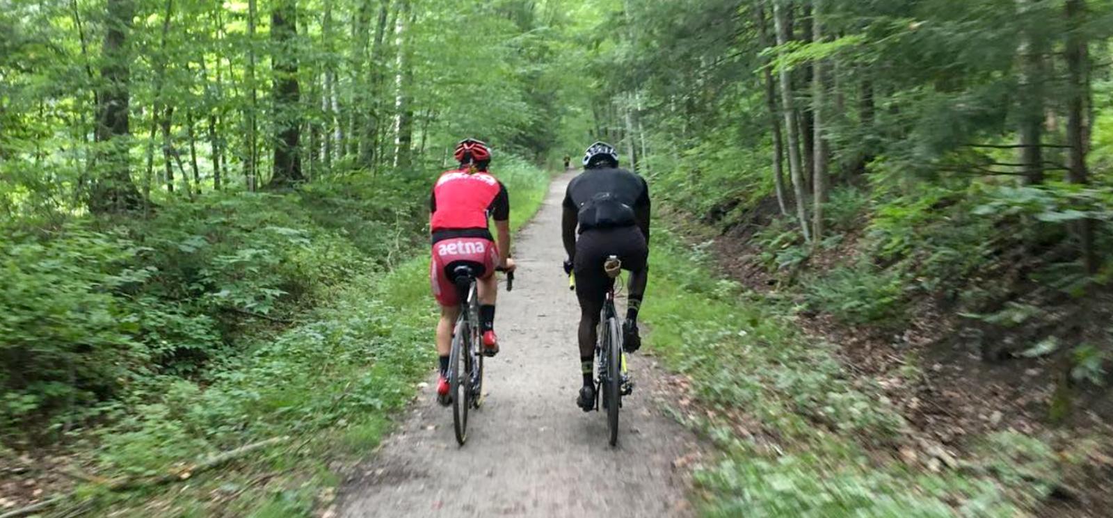 Two bicyclists riding down a path in the woods (Instagram@cyclesnack)