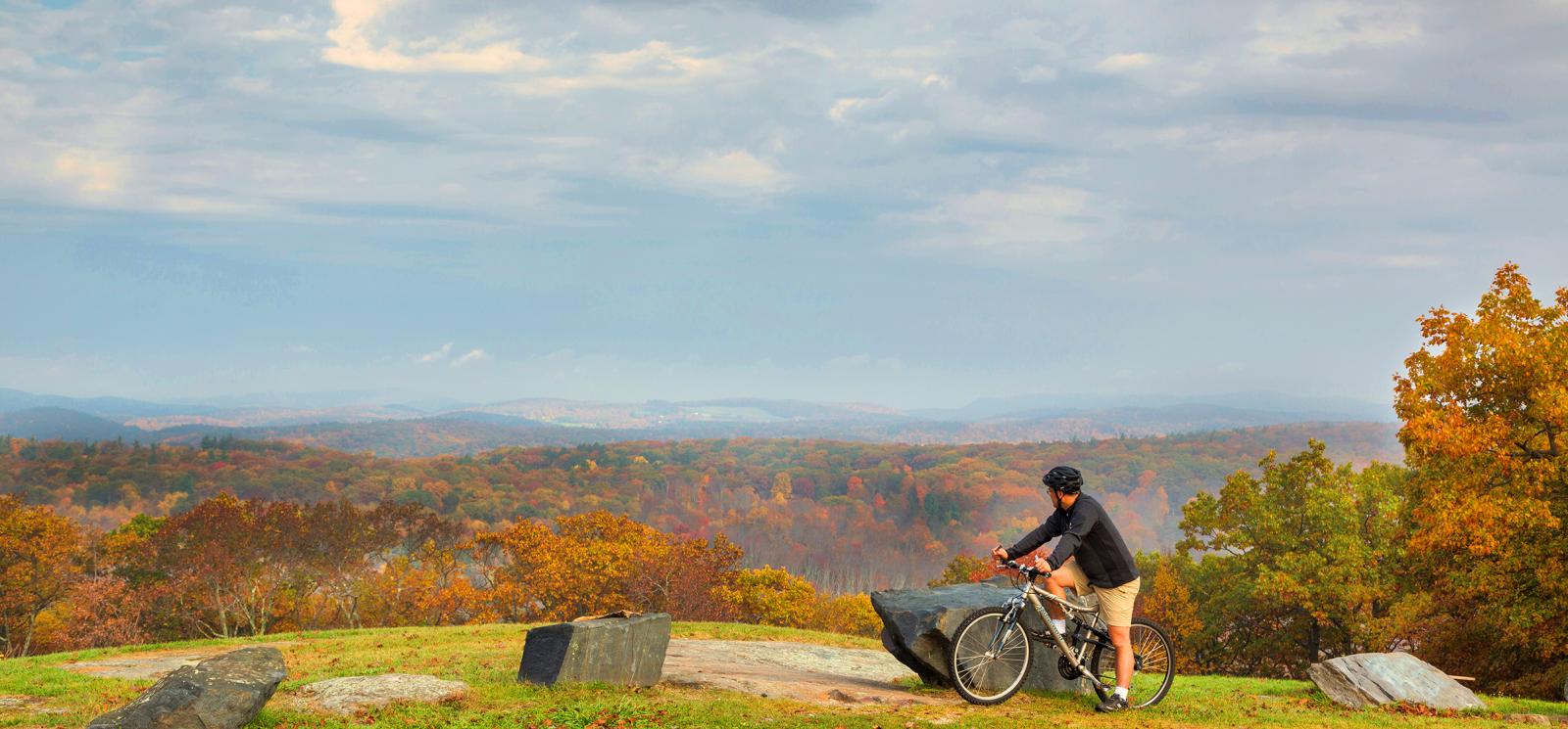 Un hombre en bicicleta en la cima de la montaña contempla la vista (CTVisit)
