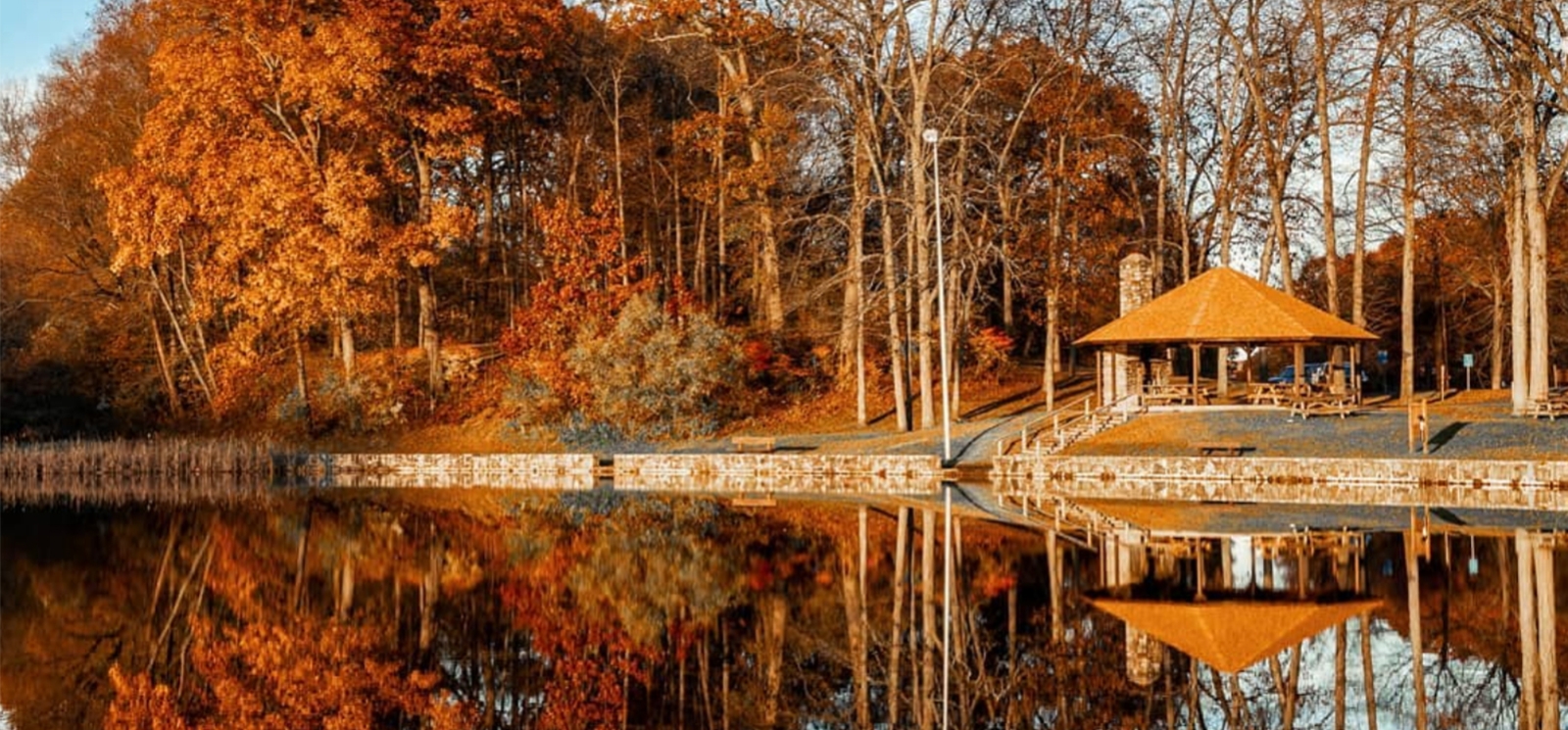 A shelter on the bank of a lake reflecting trees and sky (Instagram@kaitlyncasso)