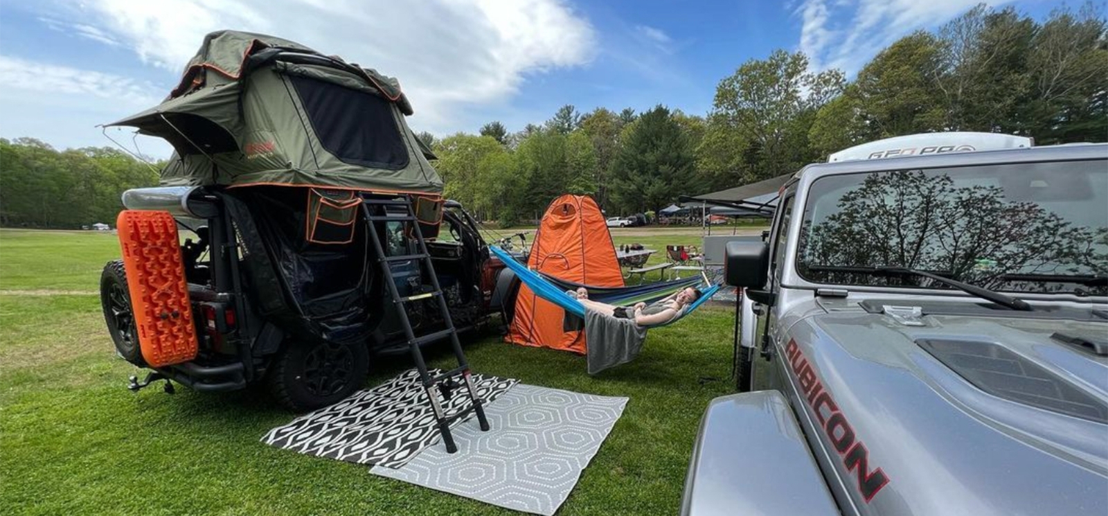 A jeep and camper on a field in summer (Instagram@jeepin_new_england)