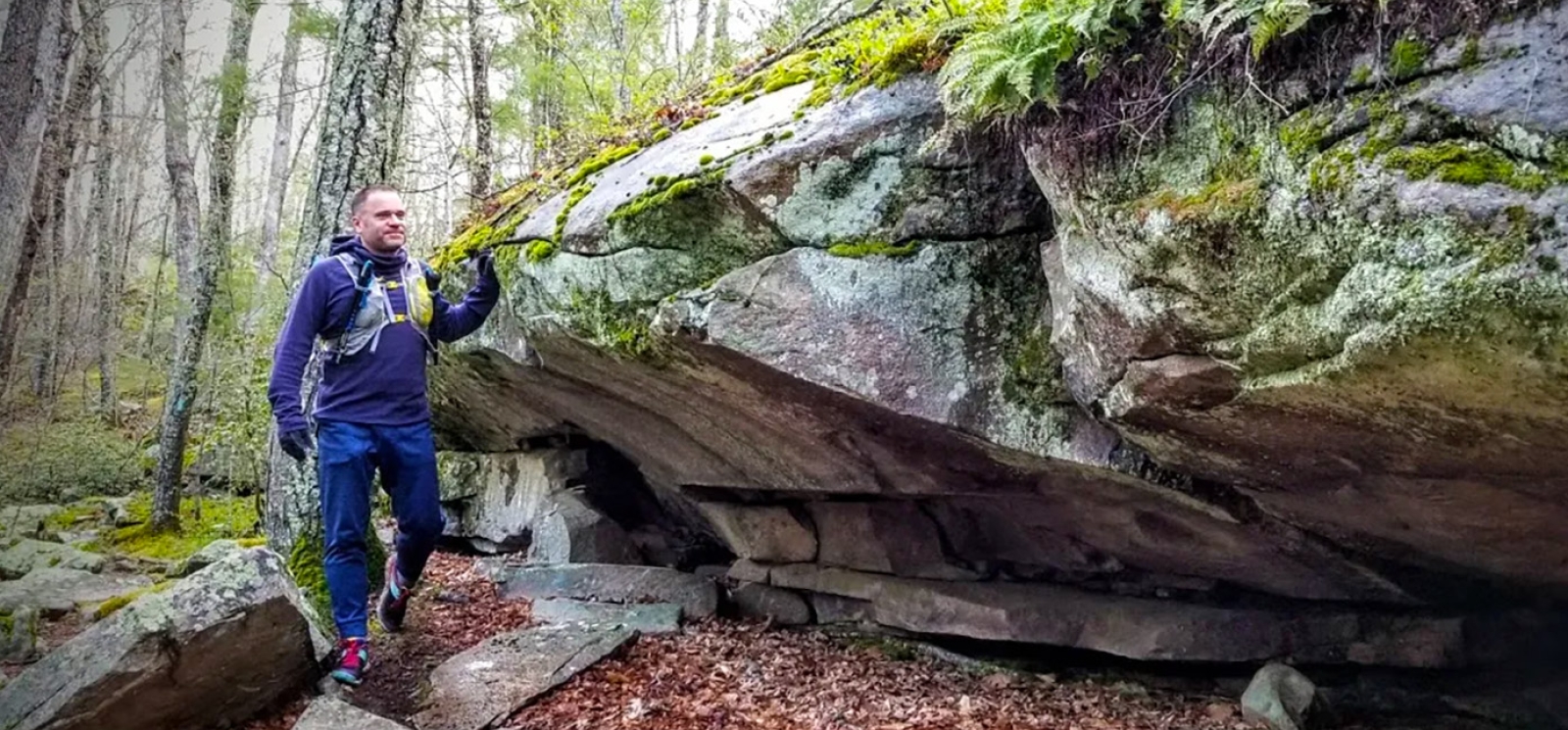 Man hiking along rock formation at Nehantic State Forest