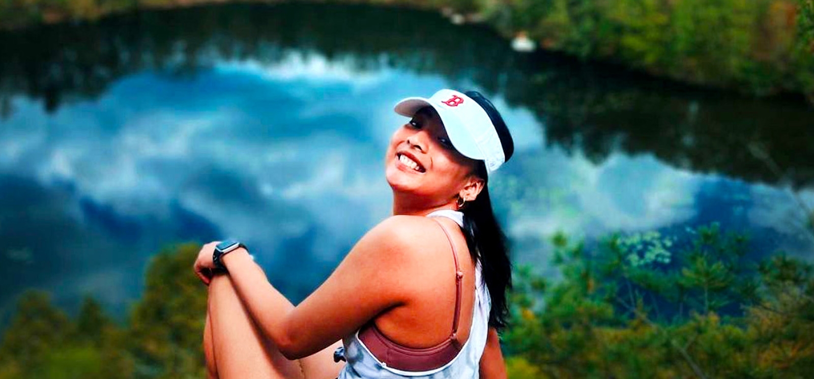 A woman enjoying the view of a pond while sitting on a scenic overlook.