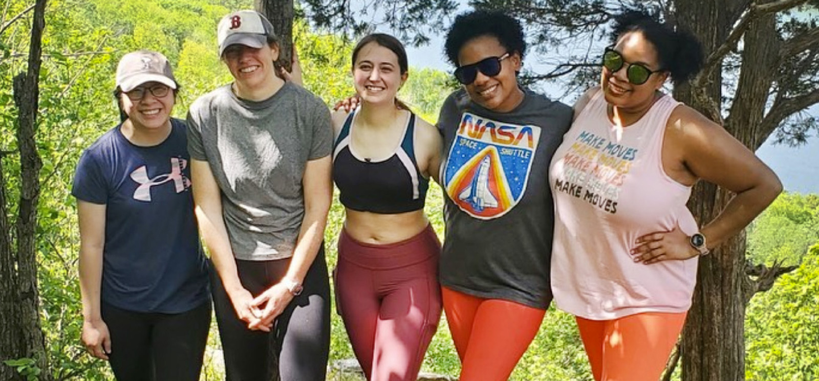 Un grupo de mujeres sonriendo y posando para una foto mientras caminan por un sendero panorámico.