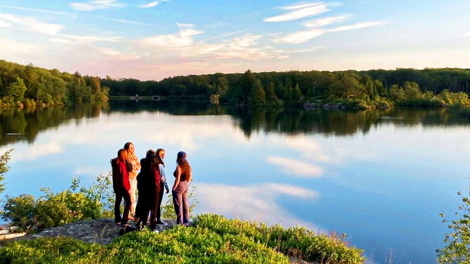 A group of girls admiring the water while taking a pause from a hike.