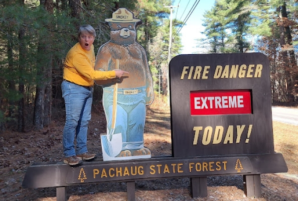 hiker with smokey the bear in front of extreme fire danger sign