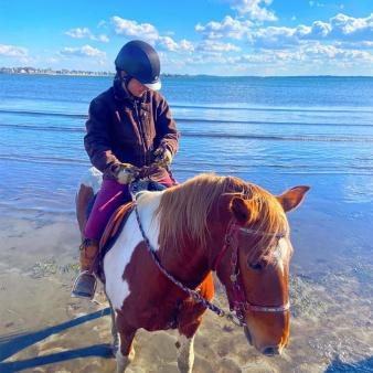 Chica montando a caballo a lo largo de la costa en Bluff Point State Park (Instagram@b.madore05)