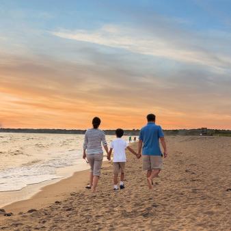 Family walking down Hammonassett Beach at sunset