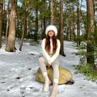 Chica adolescente con gorro de invierno sentada en una roca en la nieve (Instagram@daya.obando)