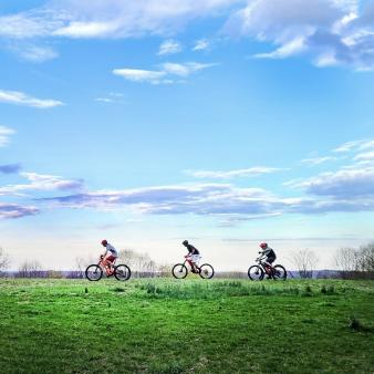 Niños en bicicleta sobre césped verde con cielo azul (Instagram@riding4fun)