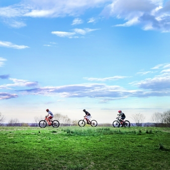 Kids biking on green grass with blue sky (Instagram@riding4fun)