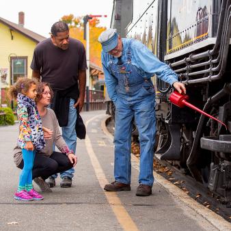 A family watching train engineer oil train wheels 