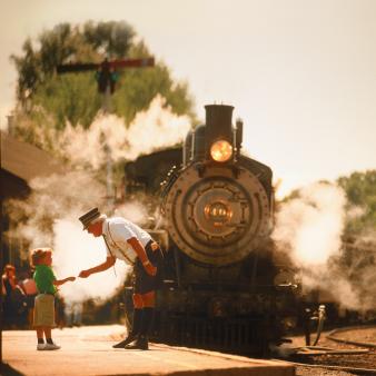 A train engineer and child on platform near approaching train (CTVisit)