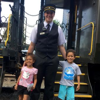 Two kids with train conductor in front of train (Instagram@msloist)