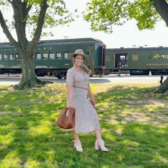A woman posing in front of a train (Instagram@coralmagiera)