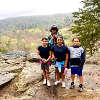 Children hiking with adult on rock with scenic view in background (Instagram@kleelee19_0)