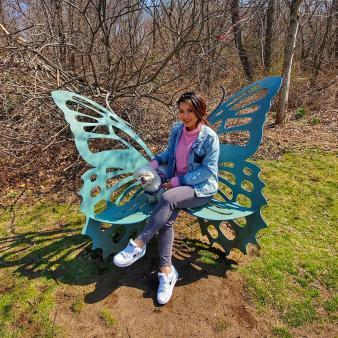 a woman sitting on butterfly bench with her dog (Instagram@trucedeoufxo)