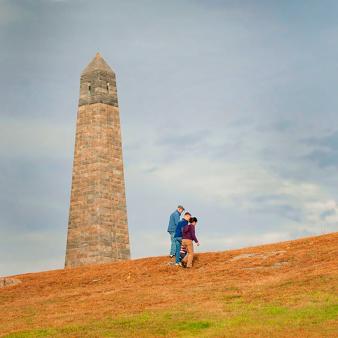 Three people walking up hill near a monument (Facebook)