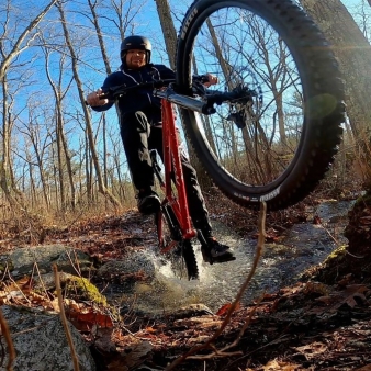 A man mountain biking splashing through water (Instagram@jamiecouture)