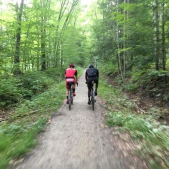 Two bicyclists riding down a path in the woods (Instagram@cyclesnack)