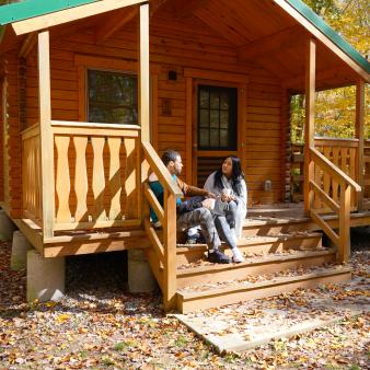 Couple enjoying cup of coffee on the porch at Hopeville Pond campground/cabin
