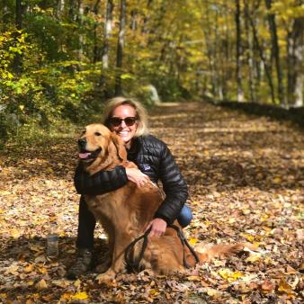 A woman hugging her dog on a leaf covered path in the woods (Instagram@randikayecnn)
