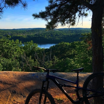 A bike parked on peak overlooking trees and water (Instagram@shanegkins)