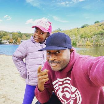 A father and daughter pose for a picture in front of the water (Instagram@motivationjuice7)