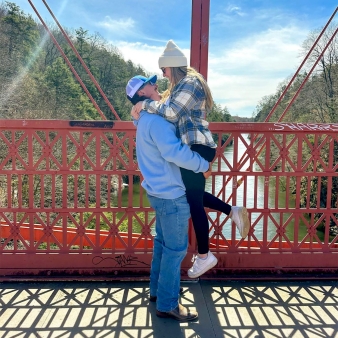 Two people hugging on a bridge in the sun (Instagram@jacquelyynt)