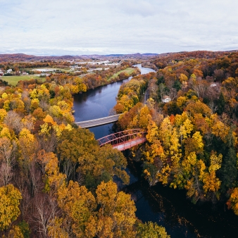 Vista aérea del follaje de otoño y el puente sobre un río (CTVisit)